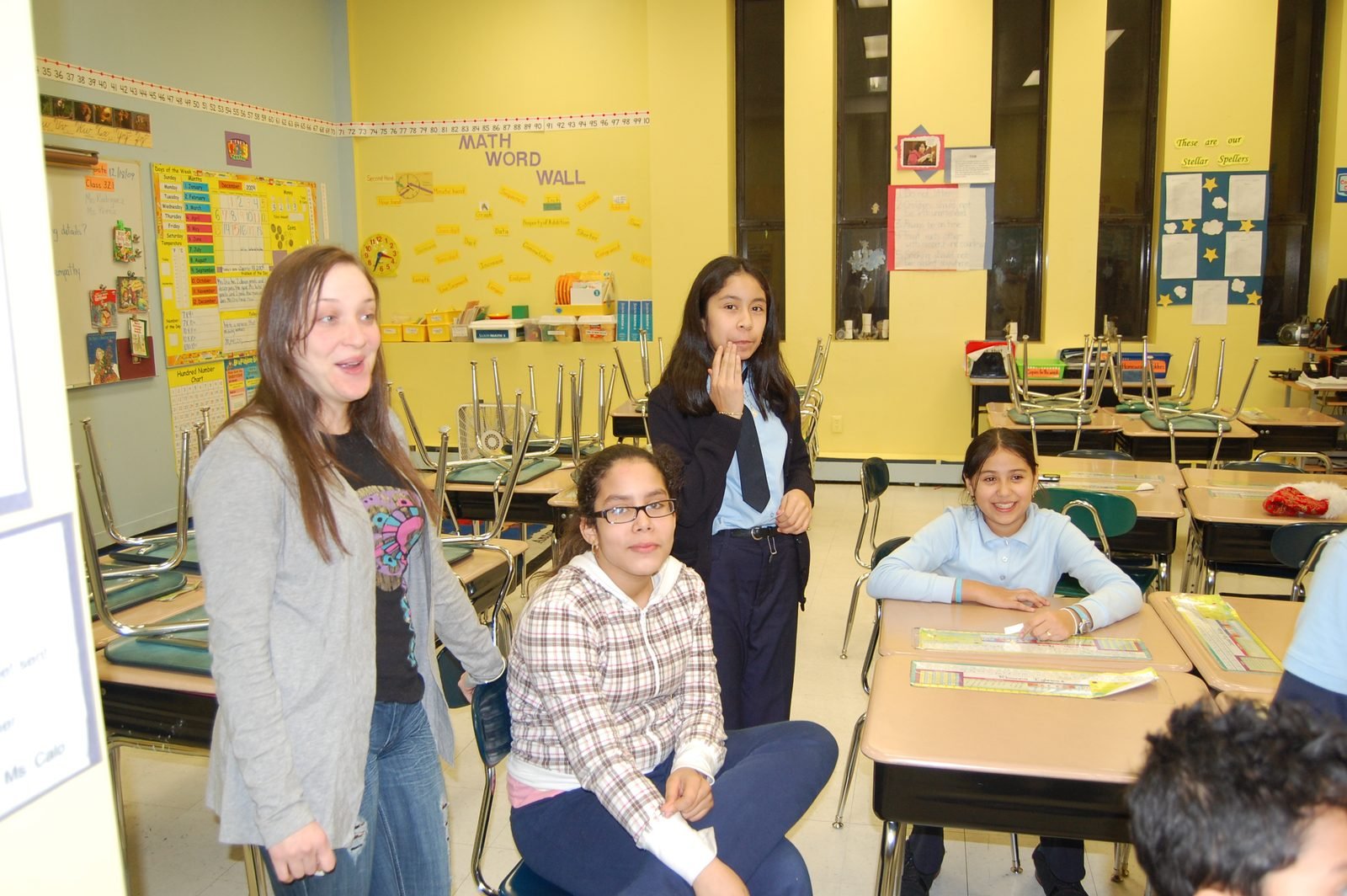 A BOOM mentor works with mentees at their desks during a site-based session.