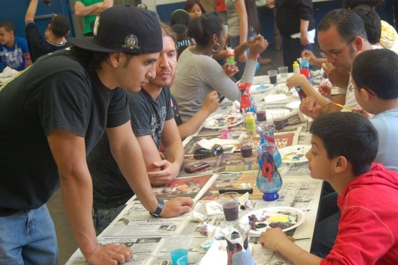 Mentors and mentees working on a craft project along a long table.