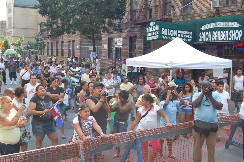 A busy Bronx street festival with vendor tents lining the road.