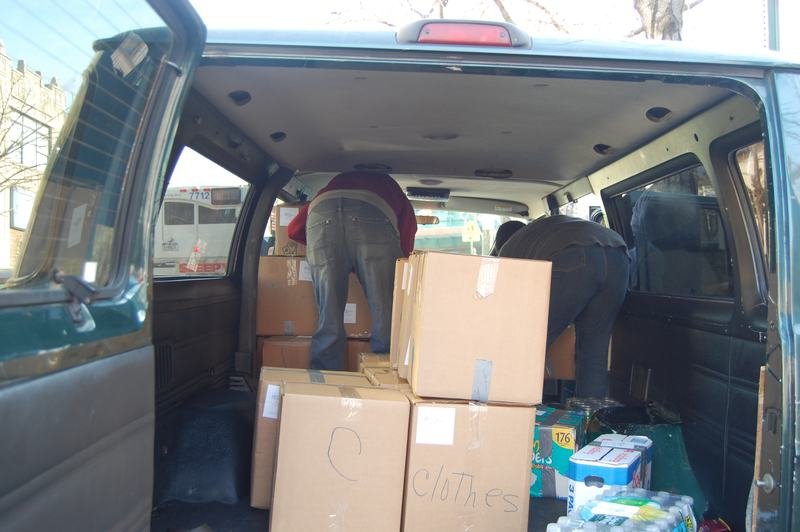The inside of a van filled with labelled cardboard donation boxes and bottled water.
