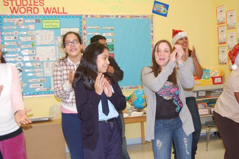 Two mentees clapping and laughing during the classroom holiday party.