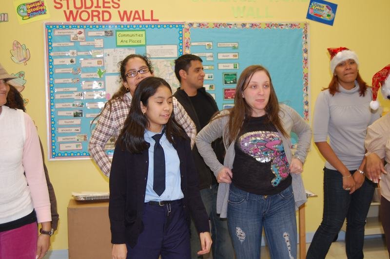 Mentors and mentees dancing in front of a studies word wall, several in Santa hats.