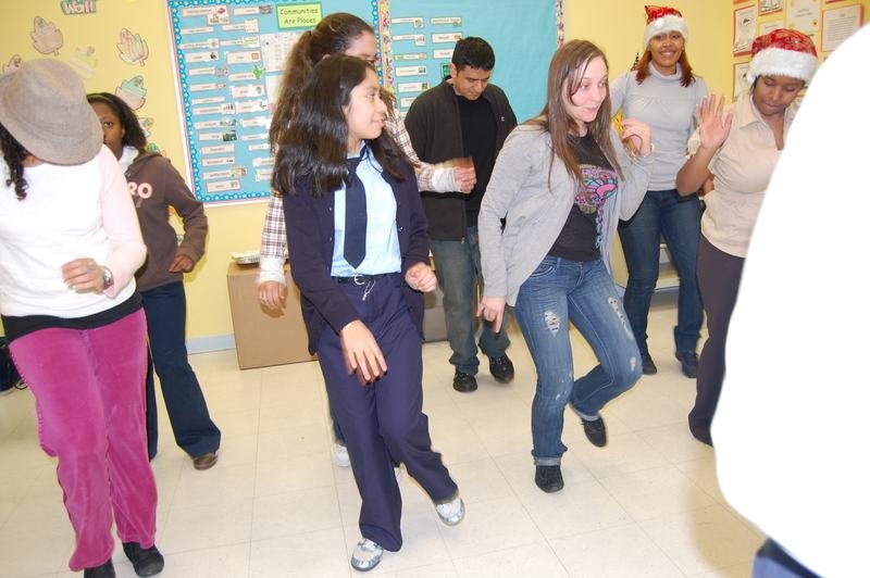 Mentors and mentees dancing in a classroom decorated for the holidays.