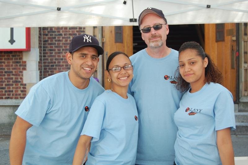 Four members of the ALANY outreach team in blue t-shirts standing together on a Bronx street.